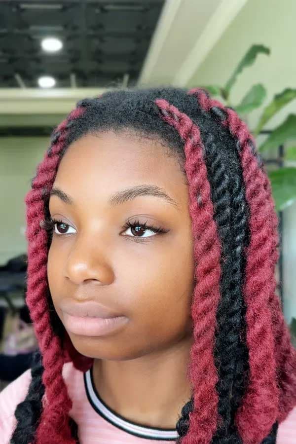 Close-up portrait of a client with red-and-black yarn braids.