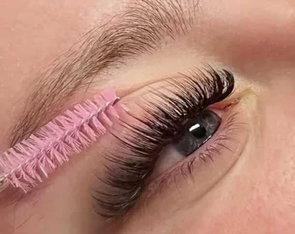 Close-up of a lash wand grooming freshly filled lash extensions.