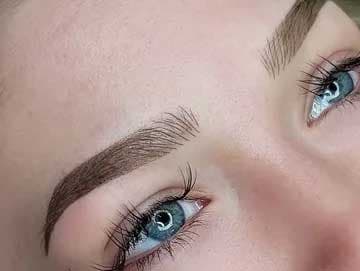 Close-up of combination brow permanent makeup blending hair strokes with shading.