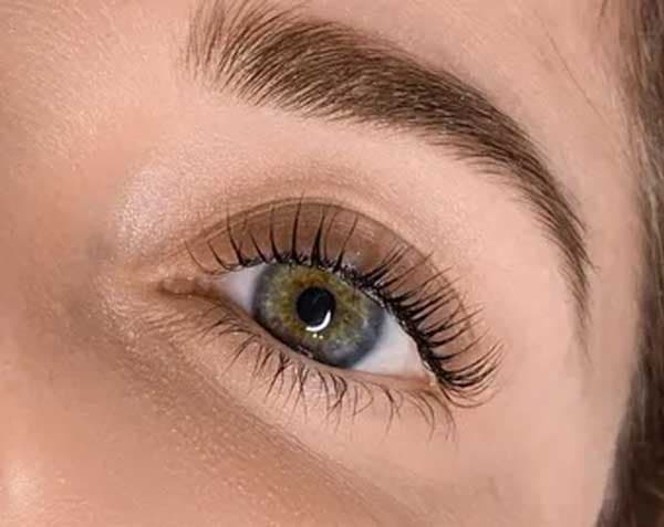 Close-up of a lash lift result on a hazel-green eye, showing curled natural lashes.